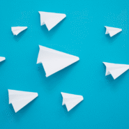 Sept avions en papier blancs volant sur un fond bleu