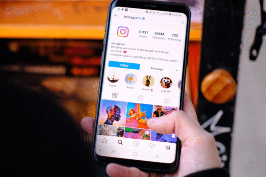 Main tenant un téléphone affichant un profil Instagram