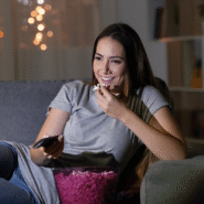 Femme souriante mangeant du pop-corn devant la télévision