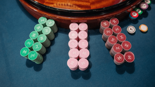 Jetons de casino verts, roses et rouges près d'une roulette