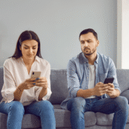 Homme et femme utilisant des smartphones sur un canapé