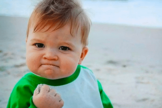 Bébé avec expression déterminée tenant du sable sur la plage