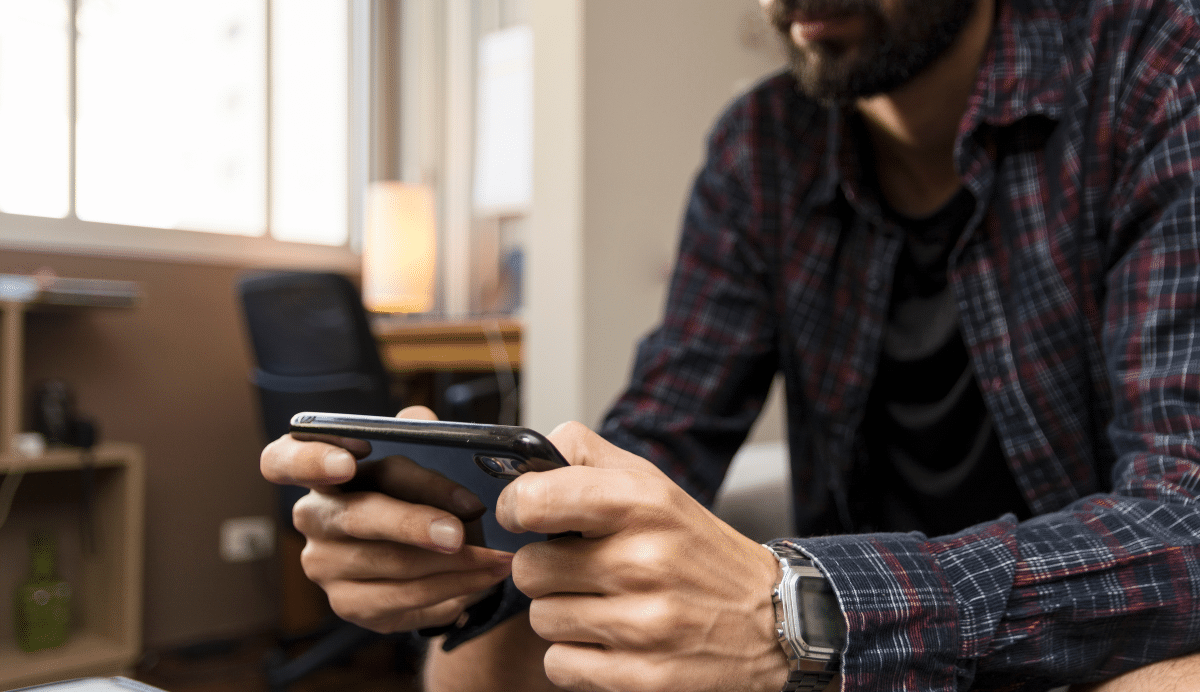 Homme barbu utilisant un smartphone dans un bureau