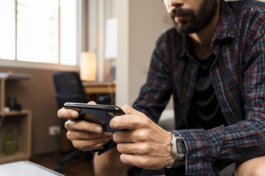 Homme barbu utilisant un smartphone dans un bureau