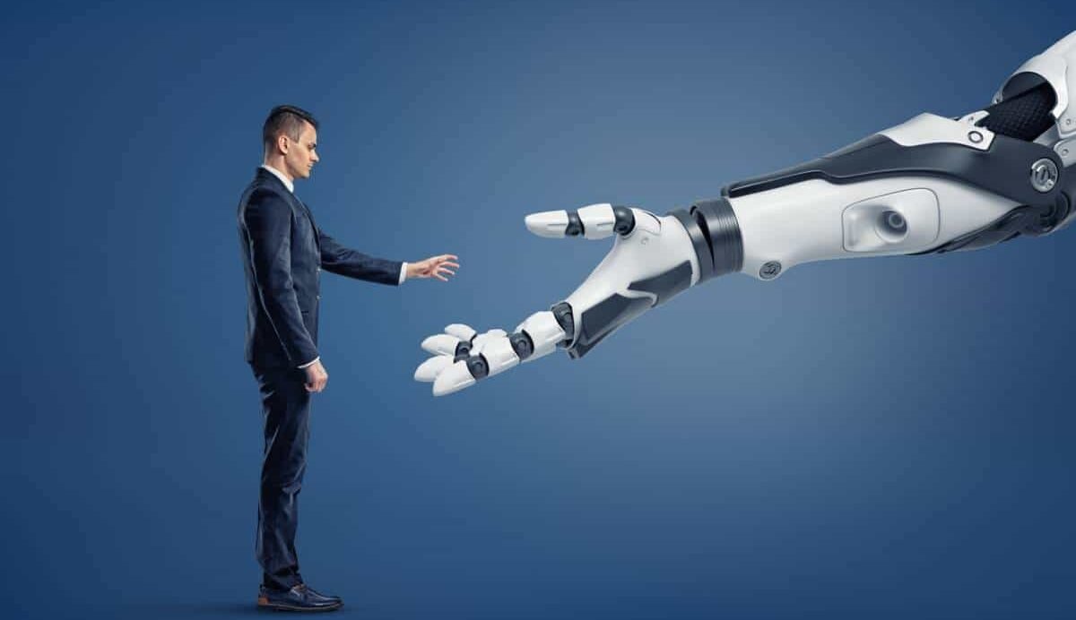 Homme en costume tendant la main vers un bras robotique