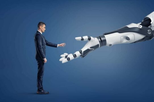 Homme en costume tendant la main vers un bras robotique