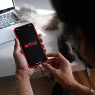 Personne utilisant Netflix sur un smartphone près d'un ordinateur portable