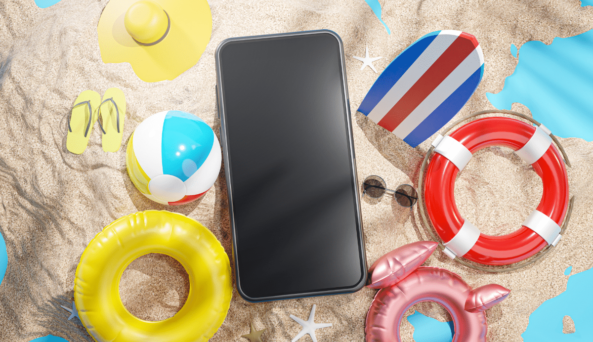 Smartphone entouré d'accessoires de plage sur le sable