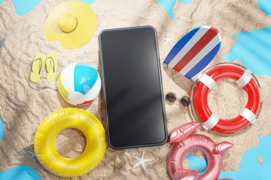 Smartphone entouré d'accessoires de plage sur le sable