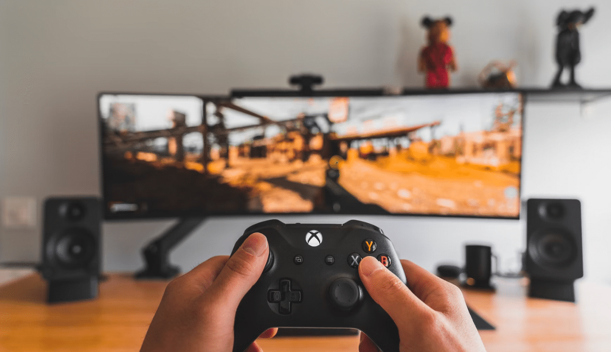 Gamer tenant une manette devant un écran large