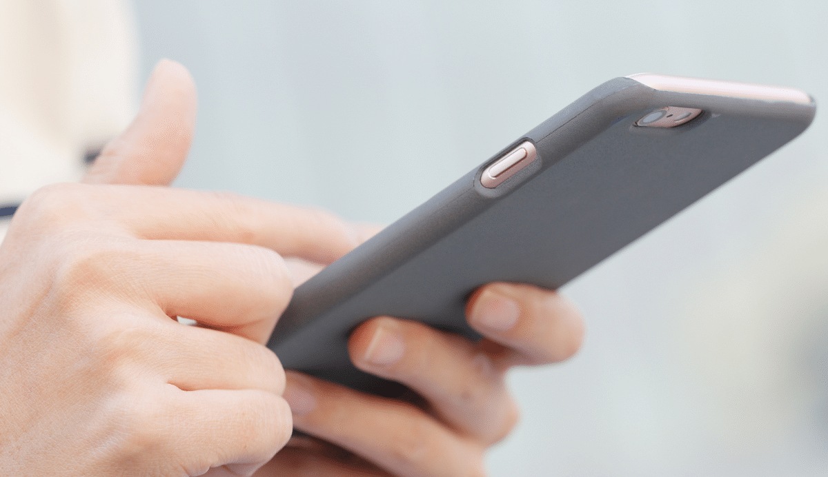 Main tenant un smartphone moderne avec une coque grise