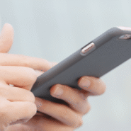 Main tenant un smartphone moderne avec une coque grise