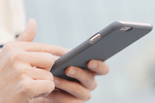 Main tenant un smartphone moderne avec une coque grise