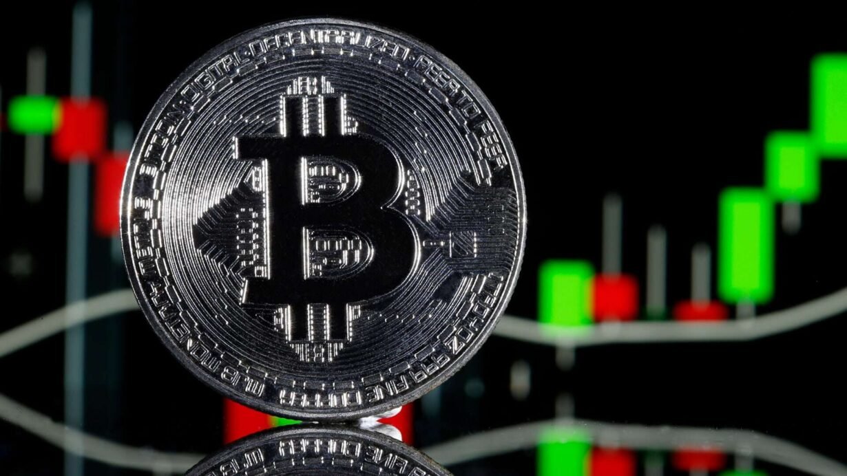 Pièce de Bitcoin devant un graphique de trading