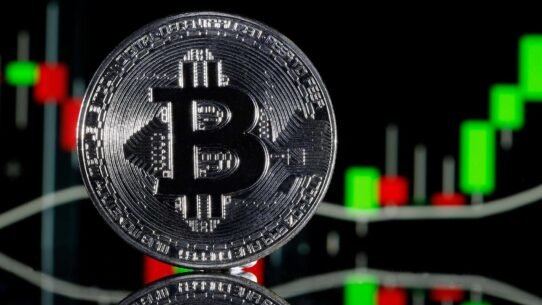Pièce de Bitcoin devant un graphique de trading