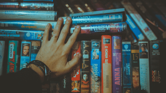 Main touchant des cassettes VHS rangées sur une étagère
