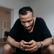 Homme souriant tenant un smartphone dans un salon