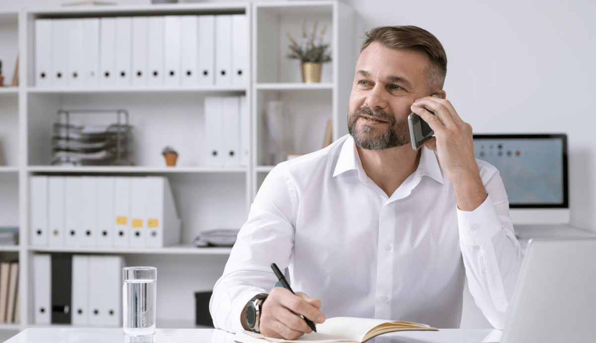 Homme souriant au bureau parlant au téléphone