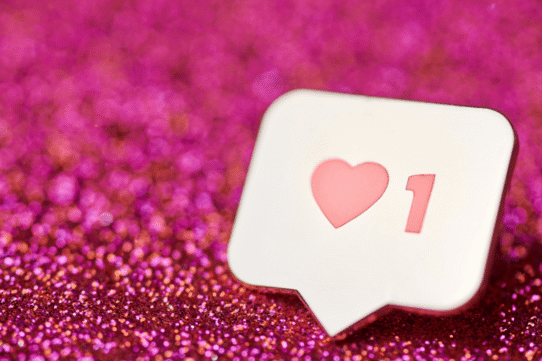 Icône de j'aime avec un cœur sur fond rose scintillant