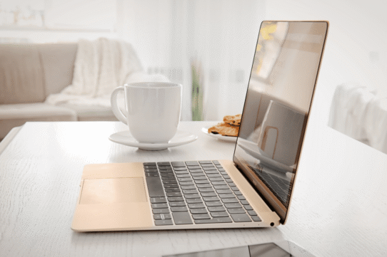 Ordinateur portable sur une table avec une tasse et des biscuits