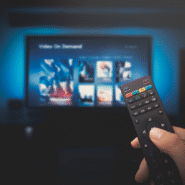 Main tenant une télécommande devant un écran de vidéo à la demande