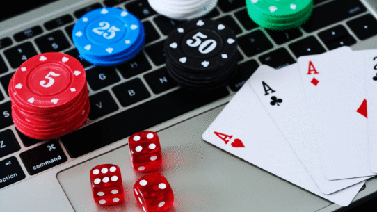 Cartes de poker, jetons et dés rouges sur un clavier d’ordinateur