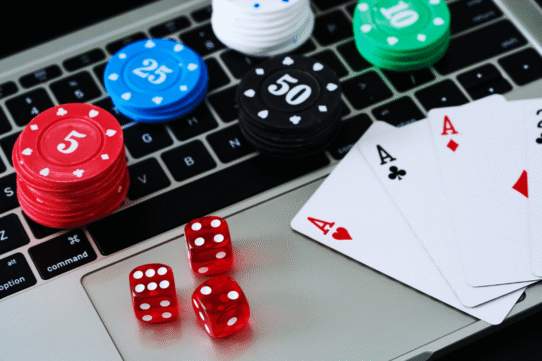 Cartes de poker, jetons et dés rouges sur un clavier d’ordinateur
