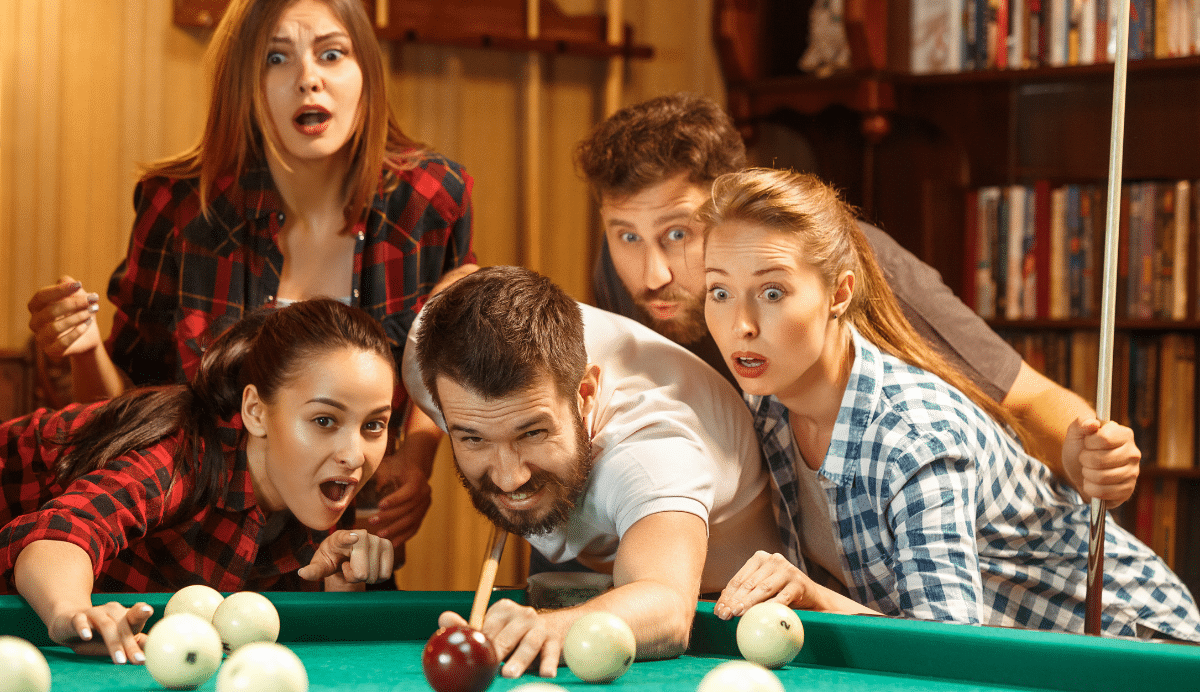 Groupe d'amis fascinés par une partie de billard