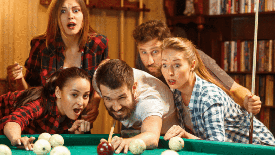 Groupe d'amis fascinés par une partie de billard