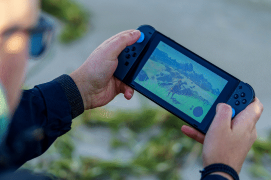Personne jouant à un jeu vidéo sur une console portable en plein air