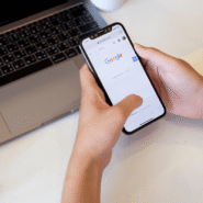 Personne utilisant Google sur un smartphone près d'un ordinateur portable