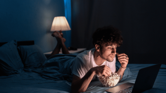 Homme mangeant du pop-corn en regardant un film sur un ordinateur portable