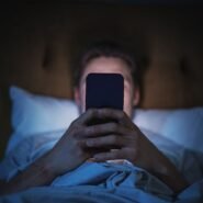 Homme allongé dans un lit regardant son smartphone la nuit
