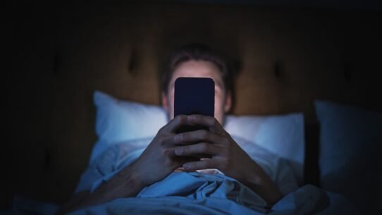 Homme allongé dans un lit regardant son smartphone la nuit