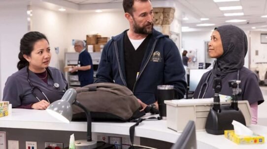 Trois professionnels de santé discutent autour d'un bureau dans un hôpital