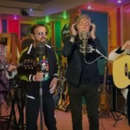 Quatre musiciens en studio avec guitares et micro