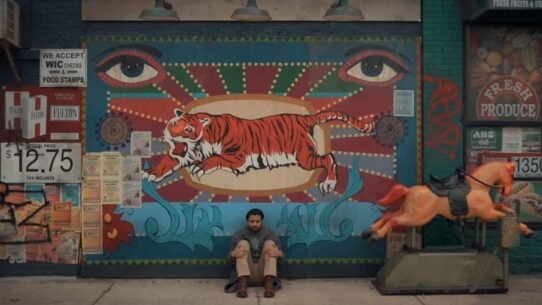 Homme assis devant une fresque murale avec un tigre et des affiches