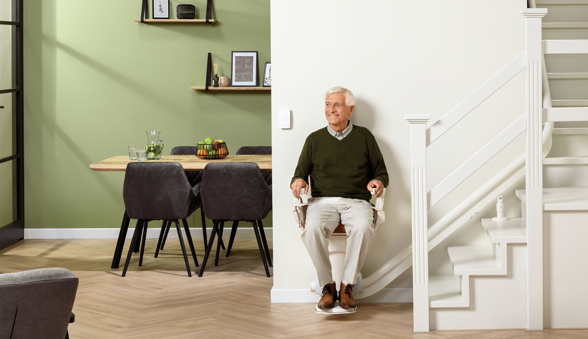 Homme souriant assis sur un monte-escalier dans un intérieur moderne