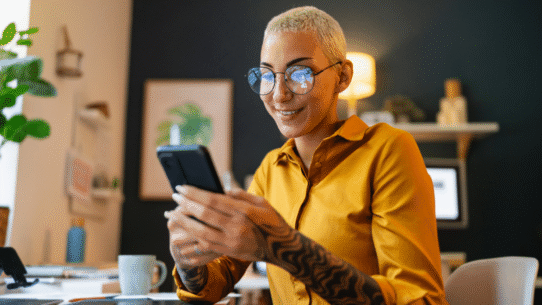 Femme souriante utilisant un smartphone dans un bureau moderne