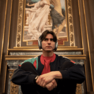 Homme avec casque audio assis devant une peinture dans un décor luxueux