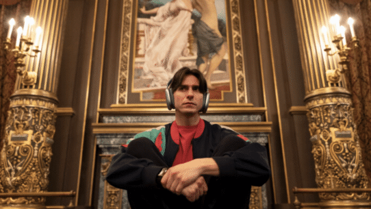 Homme avec casque audio assis devant une peinture dans un décor luxueux