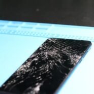 Smartphone avec écran fissuré sur une surface bleue