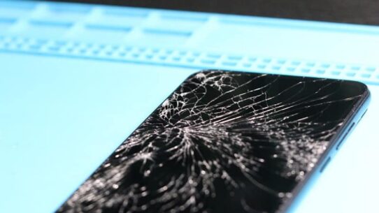 The smartphone's screen is badly cracked.