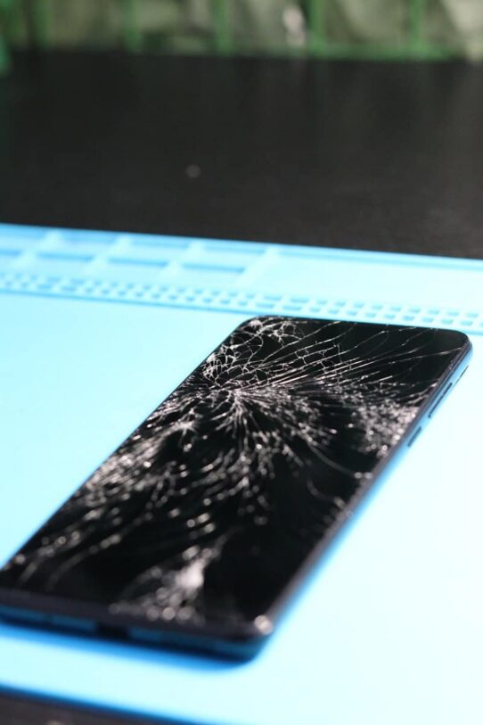 The smartphone's screen is badly cracked.