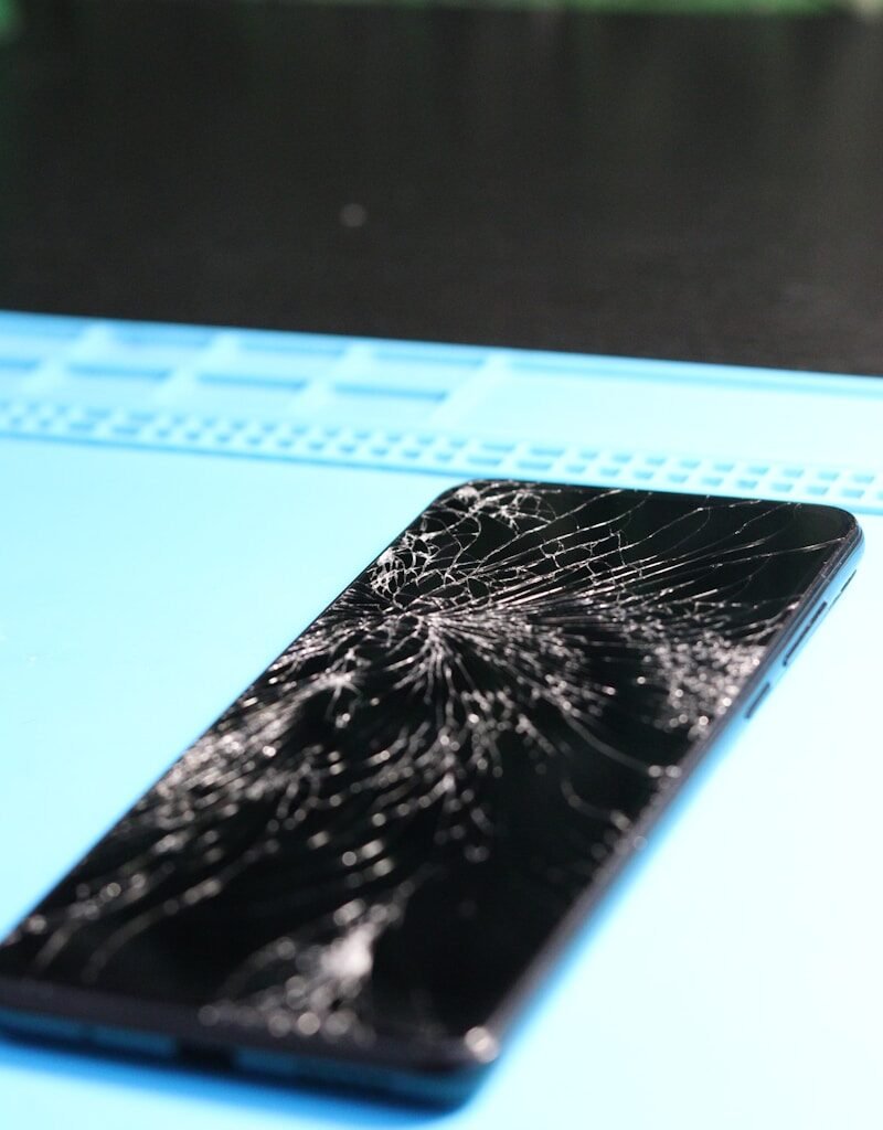 The smartphone's screen is badly cracked.