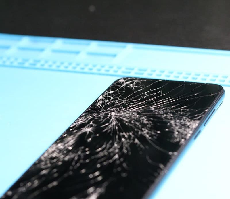 The smartphone's screen is badly cracked.