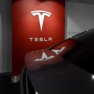 Logo Tesla blanc sur fond rouge dans un showroom