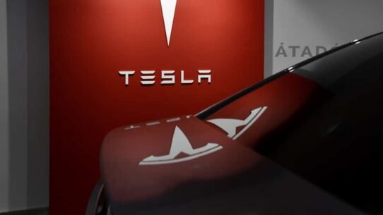 Logo Tesla blanc sur fond rouge dans un showroom