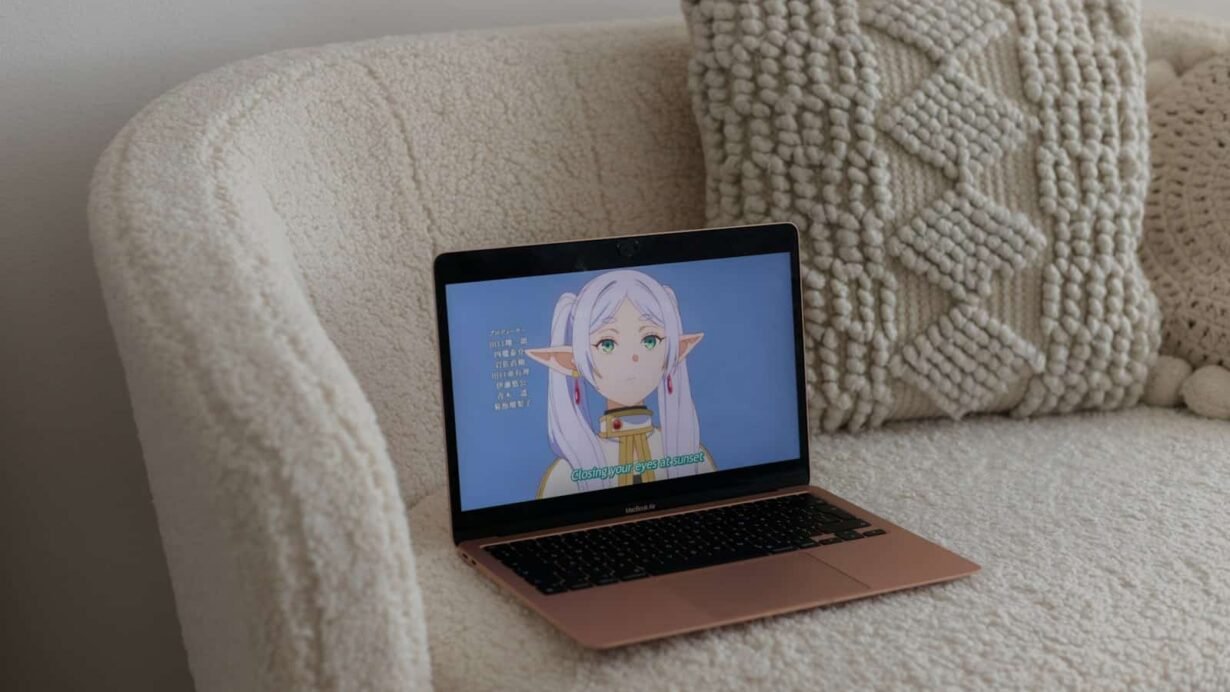 Ordinateur portable sur un canapé avec un anime affiché à l'écran