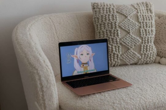 Ordinateur portable sur un canapé avec un anime affiché à l'écran